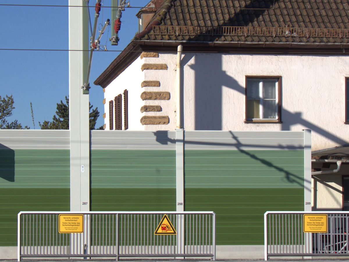 Herkömmliche, intransparente Lärmschutzwand vor Bahnhofsgebäude in Hirschaid
